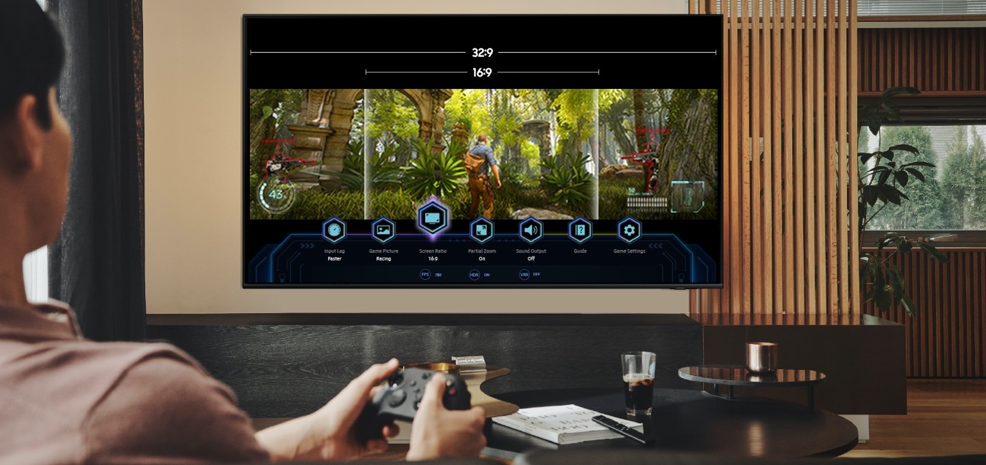 TV 정면이 보이고 화면에는 게임뷰 온스크린이 합성되어 있습니다. 화면속에는 32:9, 16:9 비율을 보여주는 텍스트가 있고 하단에는 다양한 게임바 아이콘들과 게임화면이 보입니다.