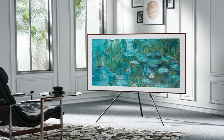 거실에 tv 와 스튜디오 스탠드가 결합된 제품이 놓여있습니다. tv 온스크린에는 명화 그림이 보입니다.