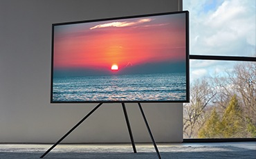 TV와 스튜디오 스탠드가 결합된 제품이 보이고 화면안에는 노을 풍경이 보입니다.