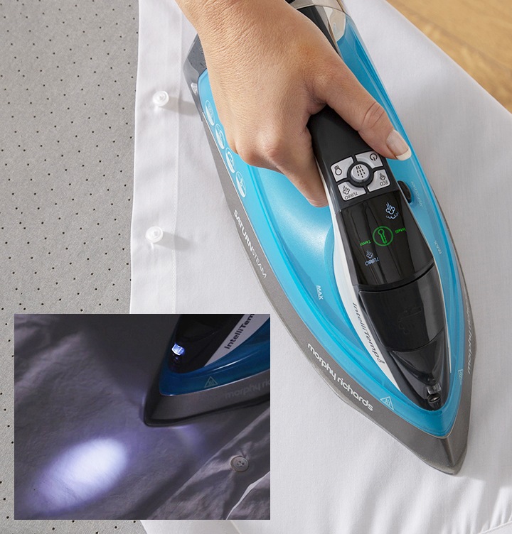 사용자가 흰색 셔츠를 새턴스팀 다리미로 다림질 하고 있습니다. 좌측 하단엔 다리미 전면부에서 조명이 나오는 모습이 보여집니다.