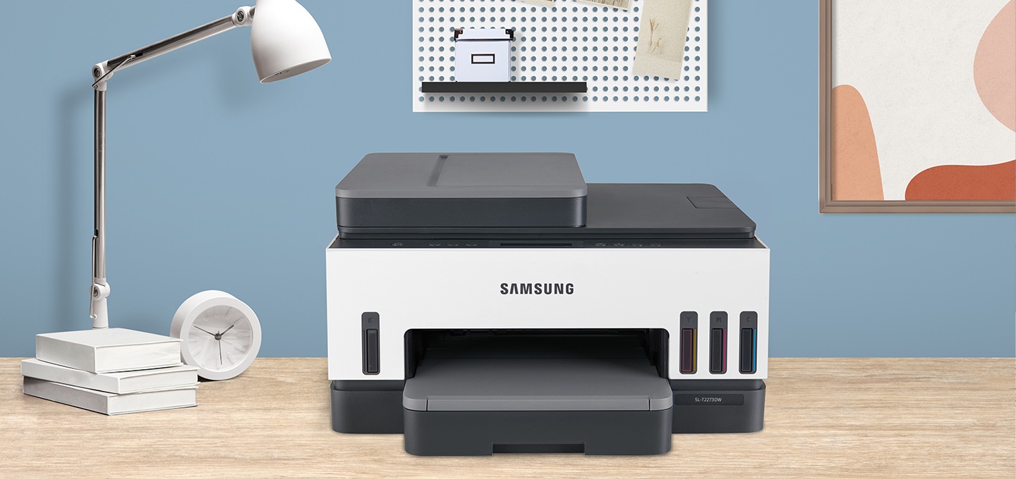 밝은 우드톤 책상 위에 잉크젯 플러스S 23/22 ppm 제품 정면이 놓여져 있습니다. 벽지는 파란색이며 주변에 사물들이 놓여져 있습니다.