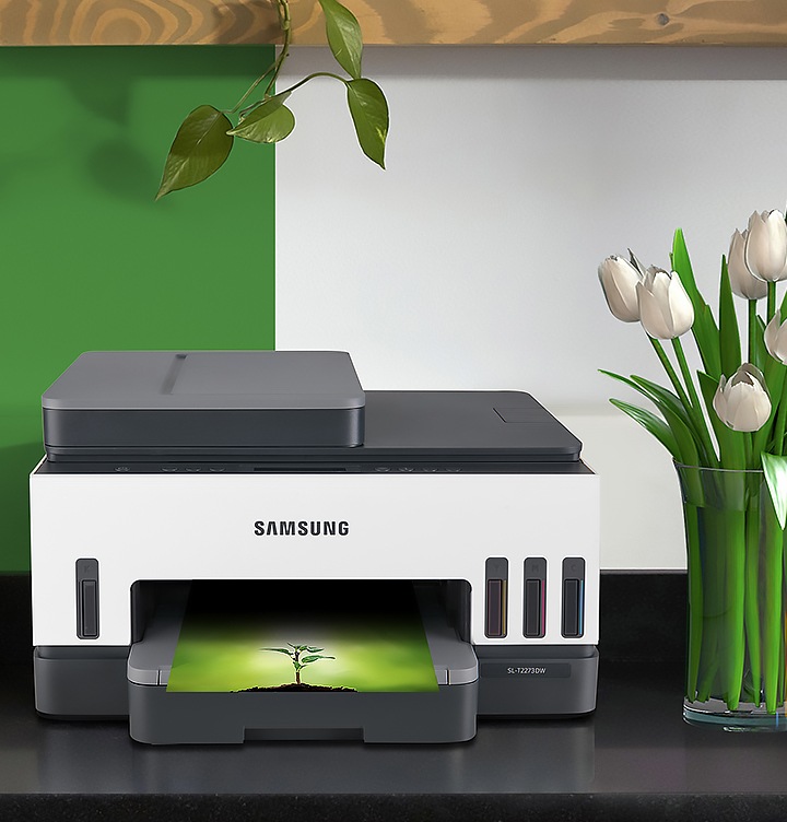 잉크젯 플러스S 23/22 ppm 제품 정면 이미지가 있습니다. 제품은 프린트를 하고 있는데 용지에는 흙위에 작은 나무 한그루가 그려져 있습니다.