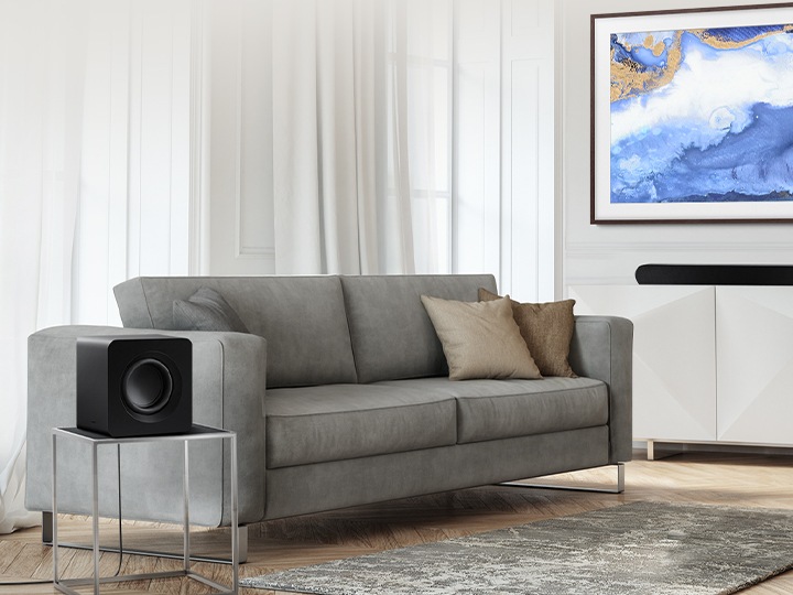 거실 선반에 사운드바가 올려져있고, 탁자 위에는 서브우퍼가 올려져있습니다.