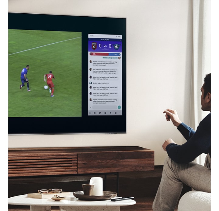 우측하단에는 구글 듀오 아이콘이 합성되어 있습니다. 우측 이미지는 벽걸이 TV 가 설치되어 있고 남성이 앉아 TV를 시청하고 있습니다. TV 온스크린에는 축구와 채팅화면이 두개로 나뉘어보입니다.
