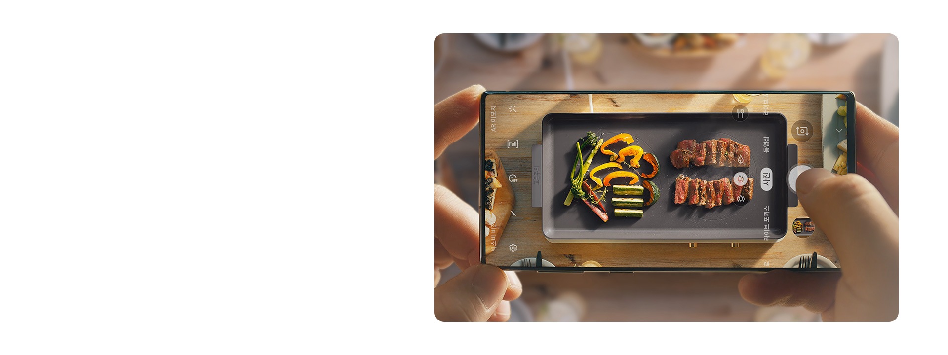 삼성 갤럭시 폰으로 더 플레이트 인덕션 위에 조리되고 있는 고기와 야채를 촬영하고 있습니다.