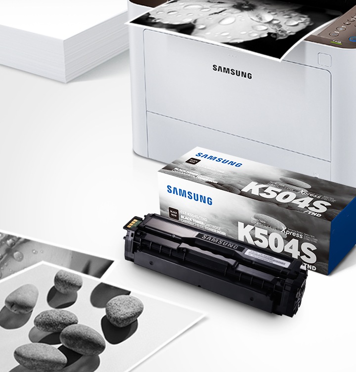 위쪽 삼성 프린터에서 출력물이 나오고 있고, 아래쪽 삼성 토너 카트리지가 있습니다.