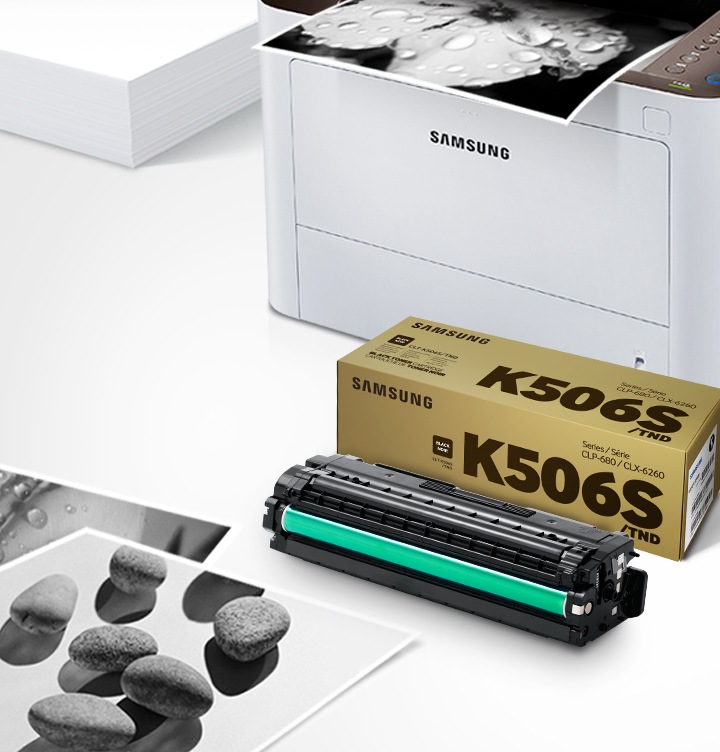 위쪽 삼성 프린터에서 출력물이 나오고 있고, 아래쪽 삼성 토너 카트리지가 있습니다.