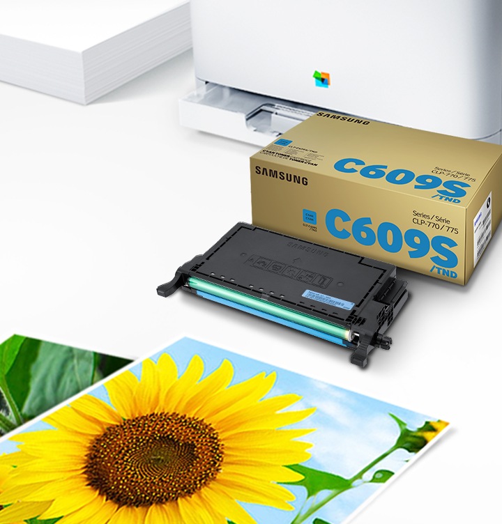 위쪽 삼성 프린터에서 출력물이 나오고 있고, 아래쪽 삼성 토너 카트리지가 있습니다.