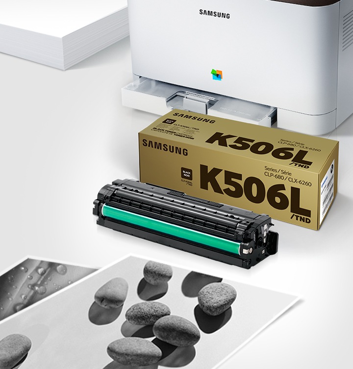 위쪽 삼성 프린터에서 출력물이 나오고 있고, 아래쪽 삼성 토너 카트리지가 있습니다.