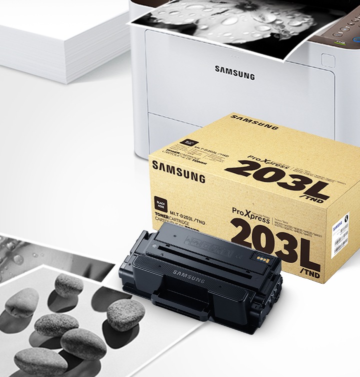 위쪽 삼성 프린터에서 출력물이 나오고 있고, 아래쪽 삼성 토너 카트리지가 있습니다.