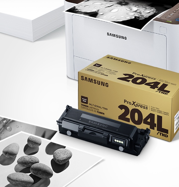 위쪽 삼성 프린터에서 출력물이 나오고 있고, 아래쪽 삼성 토너 카트리지가 있습니다.