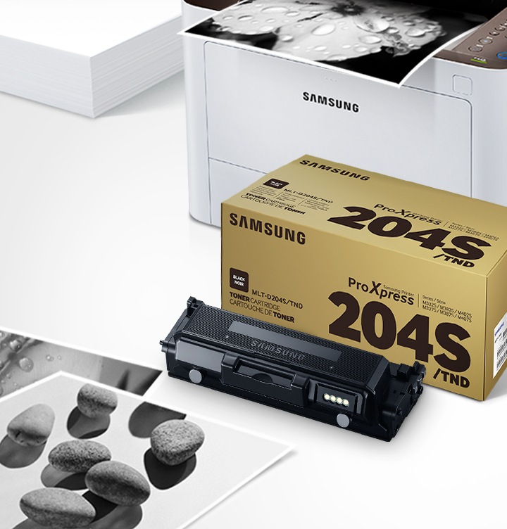 위쪽 삼성 프린터에서 출력물이 나오고 있고, 아래쪽 삼성 토너 카트리지가 있습니다.