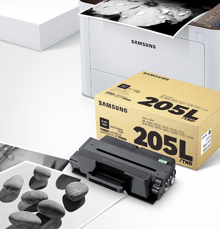 위쪽 삼성 프린터에서 출력물이 나오고 있고, 아래쪽 삼성 토너 카트리지가 있습니다.