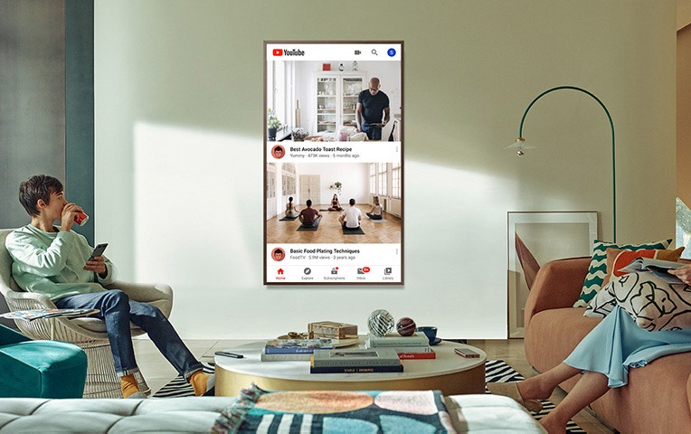 사용자들의 의자에 앉아 tv를 보고 있습니다. 벽걸이 tv는 세로모드로 설치되어 있습니다.