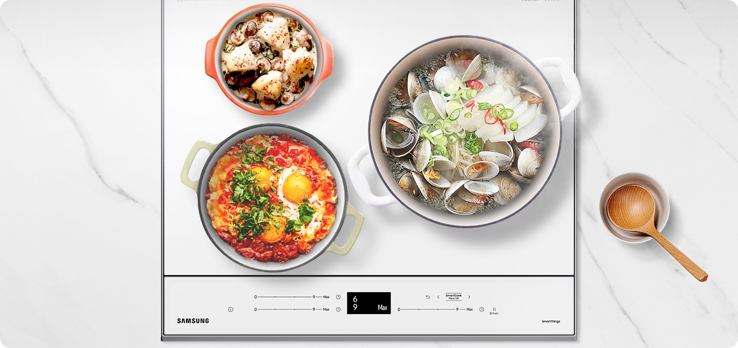 대리석 느낌의 주방상품에 설치된 BESPOKE 인덕션 빌트인 (플렉스) 글램 화이트 탑뷰가 보이며, 인덕션 우측 화구에는 조개탕이 들어있는 큰 냄비가, 좌측 화구 위에는 그라탕이 들어있는 작은 냄비, 아래에는 에그 인 더 헬이 들어있는 중간 냄비가 올려져 있습니다. 인덕션 옆으로는 우드소재의 국자가 있습니다. 