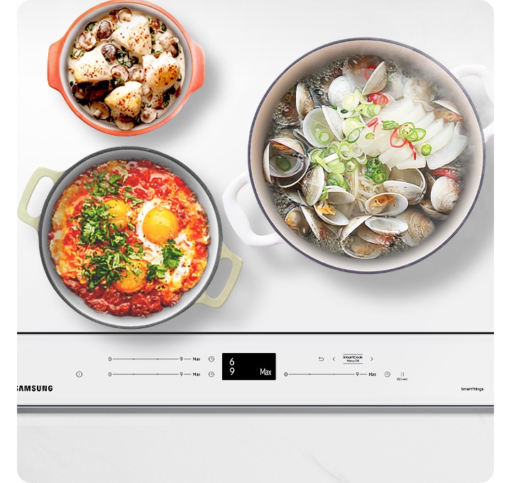 대리석 느낌의 주방상품에 설치된 BESPOKE 인덕션 빌트인 (플렉스) 글램 화이트 탑뷰가 보이며, 인덕션 우측 화구에는 조개탕이 들어있는 큰 냄비가, 좌측 화구 위에는 그라탕이 들어있는 작은 냄비, 아래에는 에그 인 더 헬이 들어있는 중간 냄비가 올려져 있습니다. 인덕션 옆으로는 우드소재의 국자가 있습니다. 