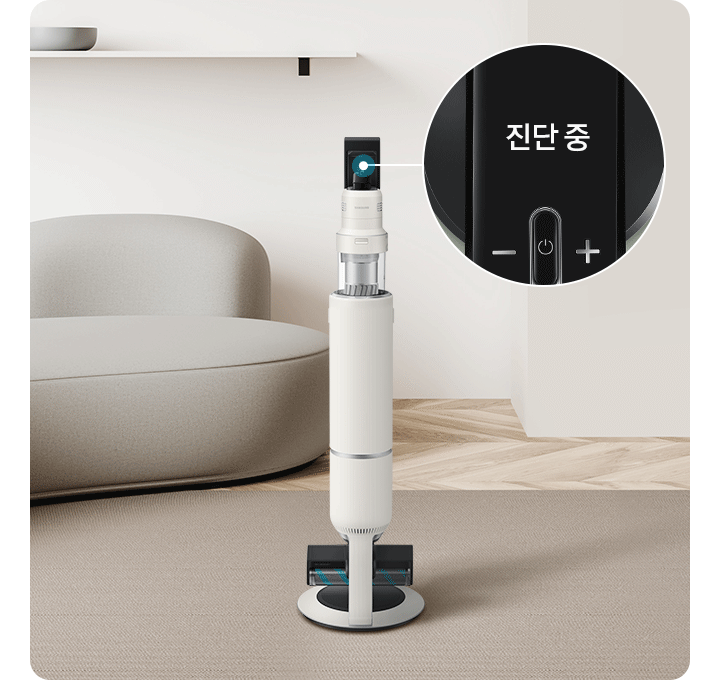 브라운그레이톤의 러그가 깔린 거실 오른쪽으로 진한 그레이톤의 동그란 협탁이 보이고 그 뒤로 동글동글한 조형감의 아이보리톤 소파가 보입니다. 벽에는 하얀 선반이 설치되어 있고 그 위에 그레이톤 보울 두 개가 올려져 있고 가장 오른쪽 구석엔 우드톤 수납장 위에 백아이보리 컬러의 화병이 있습니다. 화면 정 중앙에는 BESPOKE 제트 AI가 서있고 청소기 오른쪽으로 LCD 화면이 확대되어 보입니다.