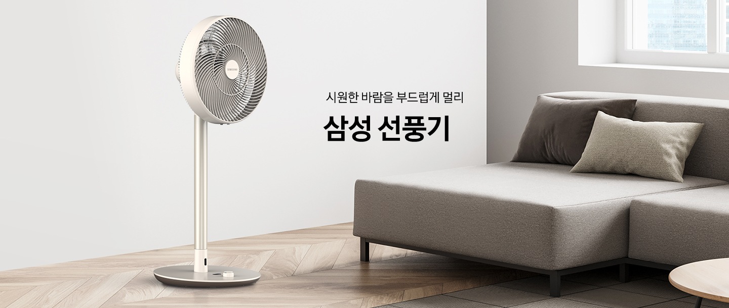 밝은 톤의 인테리어 거실에 우측으로는 패브릿 소파가 있고 좌측에는 선풍기가 있습니다. 선풍기 우측 상단에는 시원한 바람을 부드럽게 멀리 삼성 선풍기 라는 문구가 배치되어 있습니다.