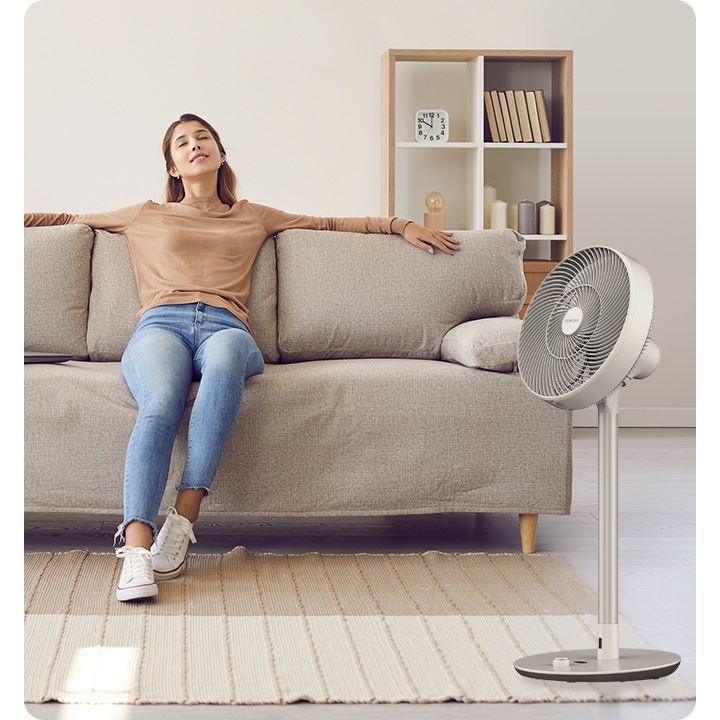 베이지톤 소파에 여성이 기대어 앉아있고 소파 옆에 선풍기가 놓여있는 이미지입니다.