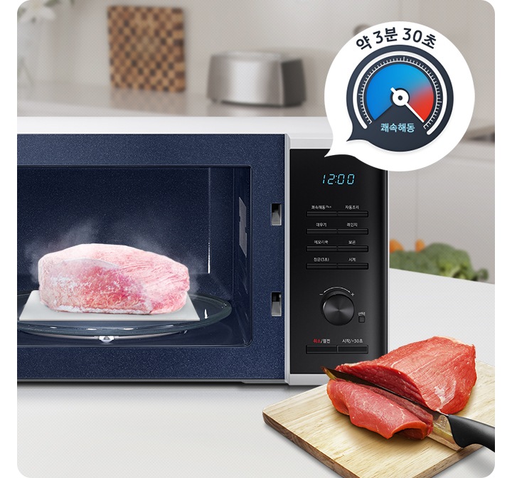 주방 아일랜드 식탁 위에 놓인 전자렌지 안에 냉동된 고기가 들어있고 약 3분 30초라는 문구가 나와있는 이미지컷입니다. 우측에는 도마 위에 생고기가 놓여있습니다.