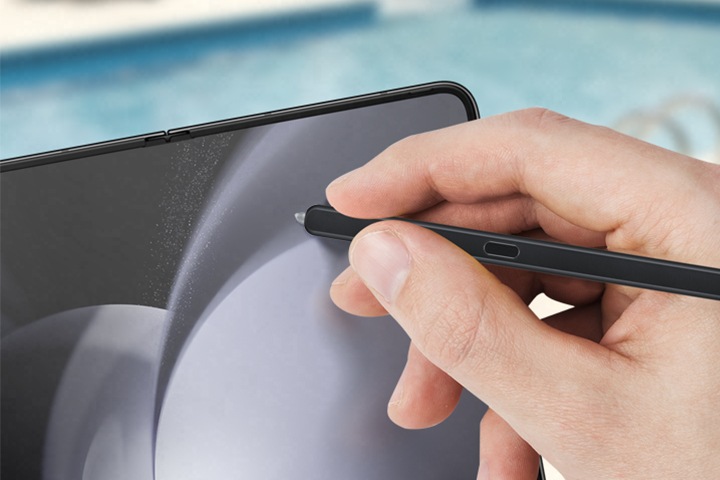 수영장 근처에서 갤럭시 Z 폴드5 S펜 폴드 에디션을 사용하는 손입니다. S펜의 방수 기능을 강조합니다. 