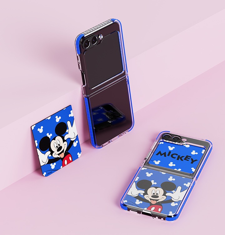 분홍색 계단식 배경이 보여집니다. 갤럭시 Z 플립5 디즈니 케이스가 장착된 갤럭시 Z 플립5 계단식에 기울어져 보여지며, 왼쪽 옆에 디즈니 플립수트 카드(블루)가 같이 기울어져 보여집니다. 오른쪽 하단에 갤럭시 Z 플립5 디즈니 케이스와 플립수트 카드가 장착된 갤럭시 Z 플립5가 펼쳐져 보여집니다.