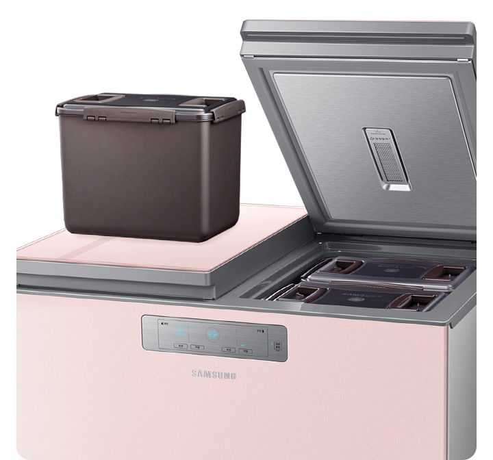 뚜껑형 김치냉장고가 열려있으며 한쪽에 김치통이 올려져 있습니다.