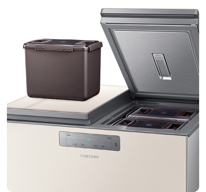 뚜껑형 김치냉장고가 열려있으며 한쪽에 김치통이 올려져 있습니다.