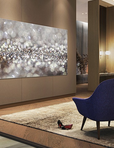 거실에 제품이 설치되어 있으며, 그 앞으로 파란색 의자가 세팅되어 있습니다.