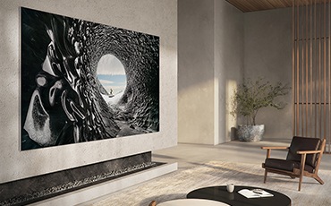 거실에 제품이 설치되어 있으며, 화면에는 동굴 외부 모습과 주변의 동굴 내부 모습이 이질감 없이 연결되어 있고, 동굴 벽면 질감이 디테일하게 표현되어 있습니다.