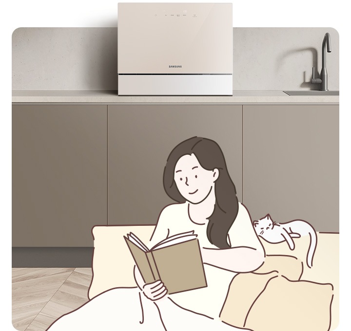 책을 읽고 있는 여성 옆에 고양이 한 마리가 쉬고 있고 그 뒤로 보여지는 주방에는 카운터탑 식기세척기가 놓여 있습니다.