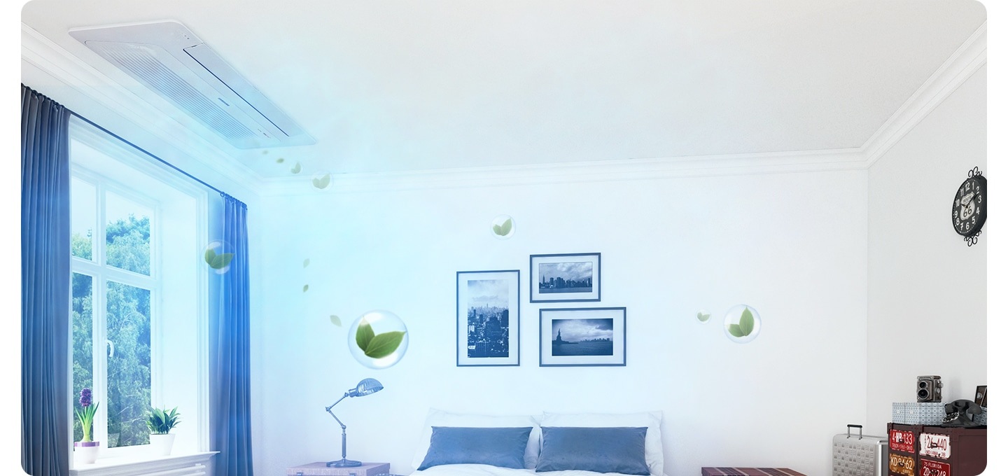 방 안으로 보여지는 공간에 좌측엔 창이 있으며 창밖엔 나무가 보여집니다 창 양쪽엔 그레이 톤의 커튼이 있고 가운데인 희색의 침대가 보여집니다. 침대위에는 두개의 흰색 배개와 그레이톤의 쿠션 2개가 보여지고 침대 헤드 위 벽에는 풍경 사진 액자 3개가 보여집니다. 우측엔 실버색상의 케리어가 보이고 그옆에 알록달록의 서랍이 보여집니다. 창가쪽 천장에 1way 천장형 시스템에어컨이 보여지며 바람문이 닫히고 무풍으로 작동 하는 듯한 형상을 하고 있습니다