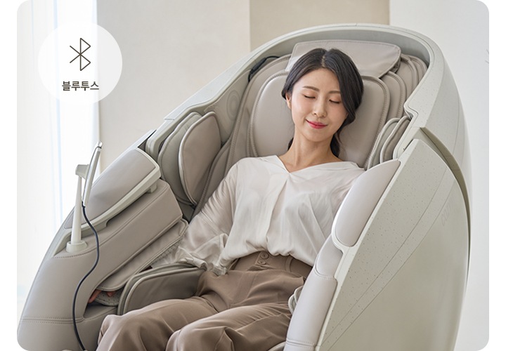 코지마 안마의자를 사용하는 여자가 보이며 오른쪽 상단에는 블루투스의 아이콘과 블루투스의 텍스트가 보입니다.