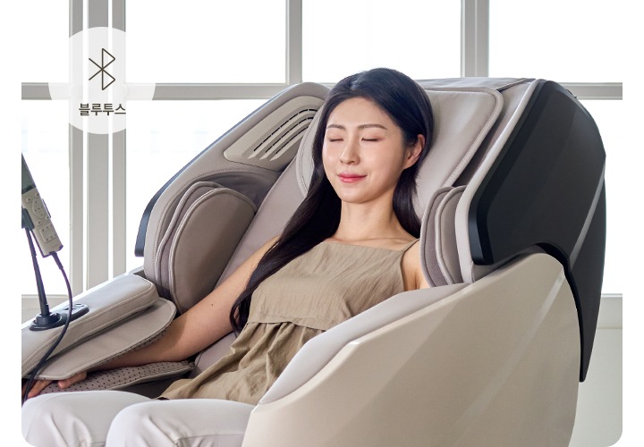 코지마 안마의자를 사용하는 여자가 보이며 오른쪽 상단에는 블루투스의 아이콘과 블루투스의 텍스트가 보입니다.