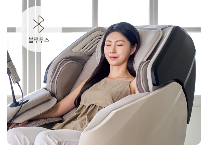 코지마 안마의자를 사용하는 여자가 보이며 오른쪽 상단에는 블루투스의 아이콘과 블루투스의 텍스트가 보입니다.