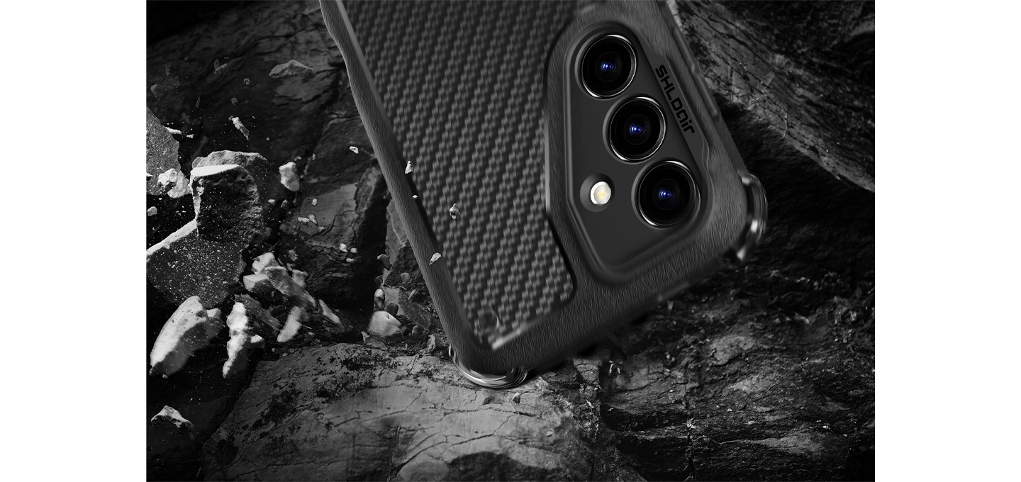 검정색 배경에 이미지 하단 부분에는 돌이 깨져서 거칠게 여기저기 흩날리고 있고 이미지 중간 상단 부분에는 갤럭시 S24 쉴드에어 러기드 케이스를 장착 후 오른쪽으로 160도 돌려 카메라 부분이 아래로 향한 정면 이미지가 하단 부분에 있는 거친 돌 위로 떨어지는 느낌을 주는 이미지입니다. 