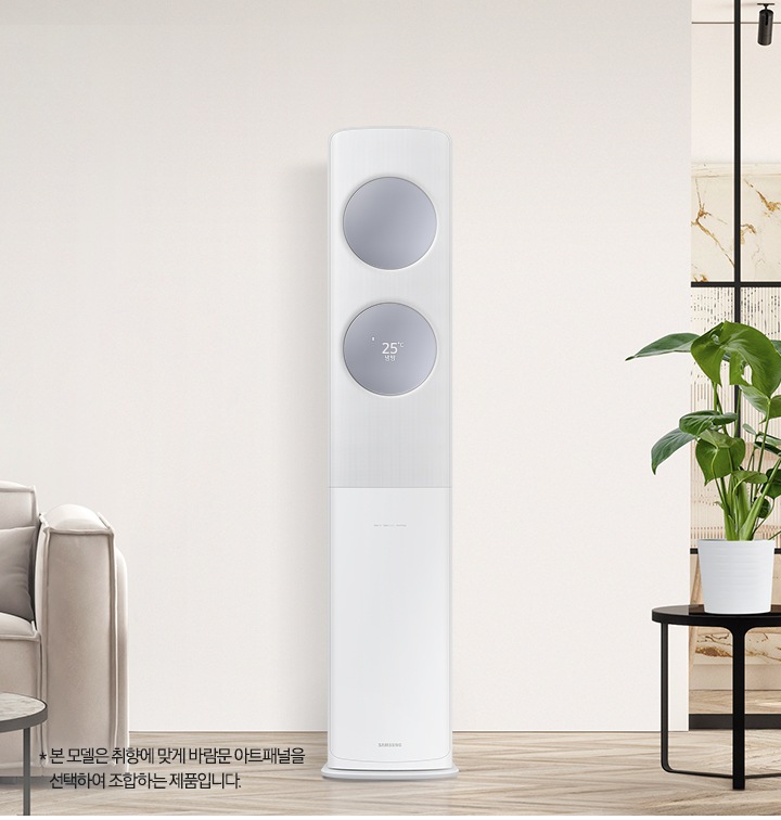 베이지 톤으로 인테리어 되어있는 공간에 좌측엔 2인용 쇼파가 보여지고 쇼파 앞에는 원형 탁자와 탁자위에 책과 화병들이 보여집니다. 가운데에는 무풍 클래식 에어컨이 위치해 있으며, 바람문은 메탈릭 블루 바람문이 장착되어 있습니다. 우측엔 다이닝 룸으로 가는 중문이 있고 그 앞에 일인용 쇼파와 작은 탁자위 화분이 함께 보여집니다