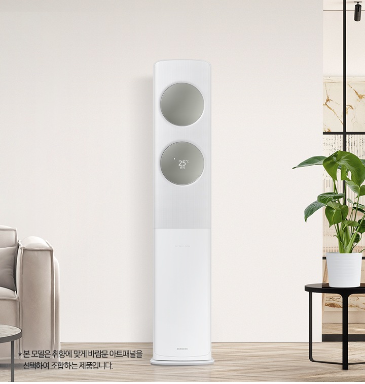 베이지 톤으로 인테리어 되어있는 공간에 좌측엔 2인용 쇼파가 보여지고 쇼파 앞에는 원형 탁자와 탁자위에 책과 화병들이 보여집니다. 가운데에는 무풍 클래식 에어컨이 위치해 있으며, 바람문은 메탈릭 세이지그린 바람문이 장착되어 있습니다. 우측엔 다이닝 룸으로 가는 중문이 있고 그 앞에 일인용 쇼파와 작은 탁자위 화분이 함께 보여집니다