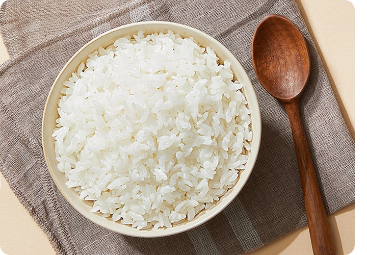 밥공기에 예쁘게 담긴 밥과 나무 숟가락 나란히 있는 이미지입니다.