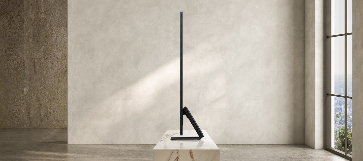 TV 우측 측면이 보입니다. TV 아래에는 장식장이 있으며 뒤로는 큰 창이 있습니다.