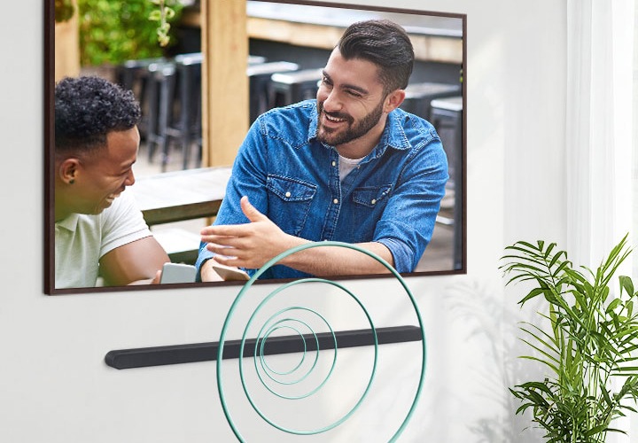 벽에 TV와 사운드바가 설치되어 있습니다. TV 화면에는 남성 두명이 대화하는 모습이 보입니다. 사운드바에서는 음향효과가 나오고 있습니다.