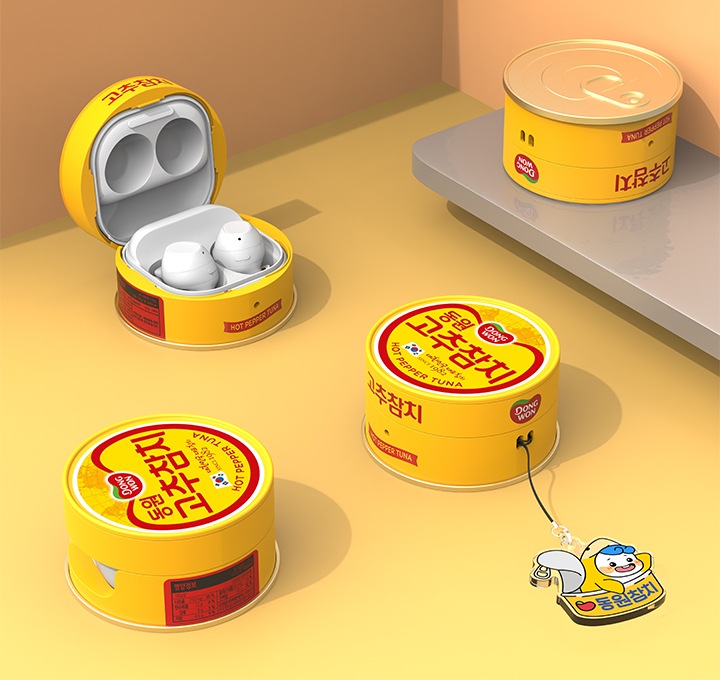 연한 주황색 벽과 연한 노란색 바닥에 이미지 오른쪽 부분에는 회색 선반이 있는 배경에 이미지 왼쪽 상단에는 갤럭시 버즈 동원 고추참치 케이스를 장착 후 열어놓은 이미지가 보이고 있고 이미지 왼쪽 하단에는 갤럭시 버즈 동원 고추참치 케이스를 장착 후 오른쪽으로 110도 돌린 후 오른쪽 위에서 내려본 이미지가 보이고 있습니다. 이미지 오른쪽 부분에 있는 선반에는 갤럭시 버즈 동원 고추참치 케이스 하단의 캔 뚜껑이 그대로 재현된 부분을 보여주고 있고 이미지 중간 부분에는 동원참치의 마스코트 ‘다랑이’ 키링을 장착한 갤럭시 버즈 동원 고추참치 케이스를 오른쪽 위에서 내려본 이미지가 보이고 있습니다.