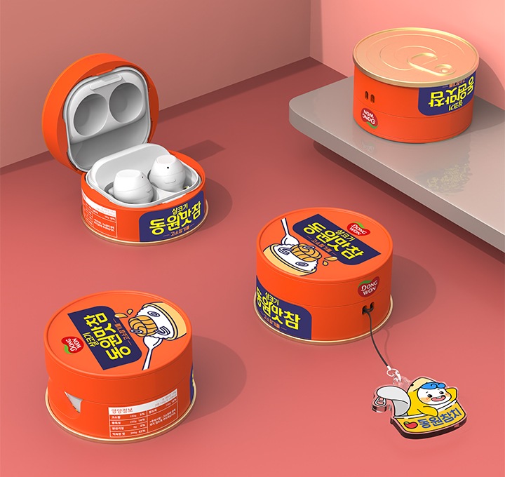 연한 핑크색 벽과 연한 다홍색 바닥에 이미지 오른쪽 부분에는 회색 선반이 있는 배경에 이미지 왼쪽 상단에는 갤럭시 버즈 동원맛참 케이스를 장착 후 열어놓은 이미지가 보이고 있고 이미지 왼쪽 하단에는 갤럭시 버즈 동원맛참 케이스를 장착 후 오른쪽으로 110도 돌린 후 오른쪽 위에서 내려본 이미지가 보이고 있습니다. 이미지 오른쪽 부분에 있는 선반에는 갤럭시 버즈 동원맛참 케이스 하단의 캔 뚜껑이 그대로 재현된 부분을 보여주고 있고 이미지 중간 부분에는 동원참치의 마스코트 ‘다랑이’ 키링을 장착한 갤럭시 버즈 동원참치 케이스를 오른쪽 위에서 내려본 이미지가 보이고 있습니다.