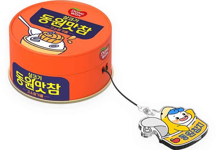 이미지 중간에서 동원참치의 마스코트 ‘다랑이’ 키링을 장착한 갤럭시 버즈 동원 동원맛참 케이스를 버즈에 장착 후 오른쪽 상단에서 내려본 이미지가 보이고 있습니다.