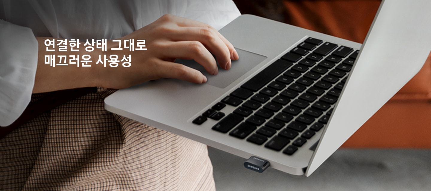 한 사람이 USB 3.1 FIT PLUS 512 GB 제품이 연결된 노트북을&nbsp;한 손으로&nbsp;들고&nbsp;다른 손으로&nbsp;작업을 하고 있는 모습을 보여주고 있습니다. 이미지 왼쪽&nbsp;상단부분에는&nbsp;약간 어두운 부분이 있고 그 위에 연결한 상태 그대로 매끄러운 사용성 텍스트가 적혀 있습니다.