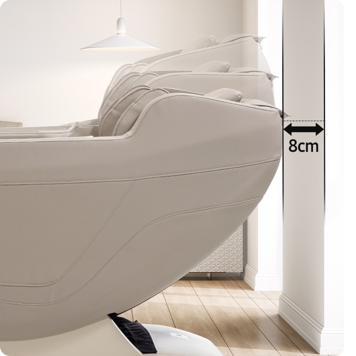 베이지 톤의 올인 안마의자 헤드부분이 확대되어 보여지며, 벽면과 안마의자 사이의  8cm 문구가 보여지며, 8cm 거기가 필요한다는것을 보여집니다.