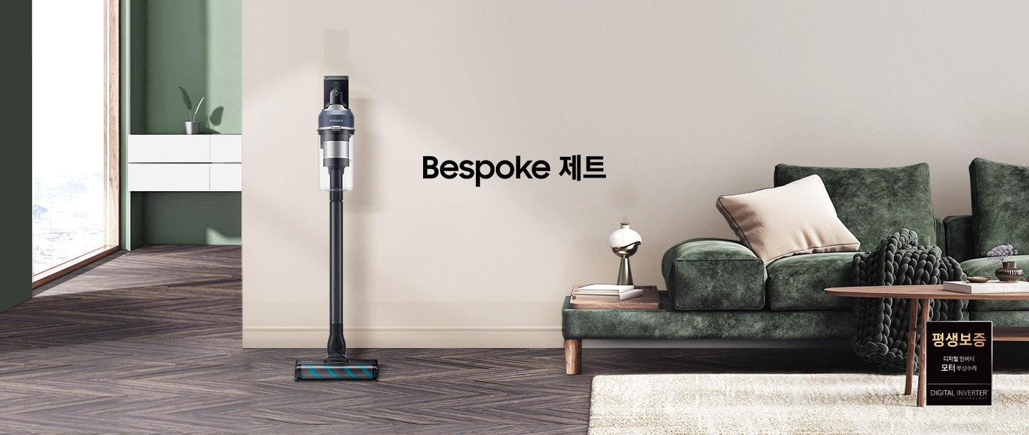 모던한 분위기의 거실이 보입니다. 왼쪽에는 해가 들어오는 넓은 창이 보이고 그 옆에는 하얀색 선반형 벽 수납장이 보입니다. 수납장 위에는 초록 잎 2장이 자라고 있는 작은 화분이 올려져 있습니다. 선반 뒤 쪽 벽은 부드럽고 잔잔한 초록색 톤을 띄고 있습니다. 마루는 헤링본 스타일의 진한 월넛 색상입니다. 정면에 보이는 넓은 벽면은 진한 아이보리 톤을 띄고 있습니다. 오른쪽 구석으로는 진한 그린 색의 패브릭 소파가 있습니다. 소파 위에는 아이보리 톤의 사각 쿠션과 굵은 짜임의 니트 재질 담요가 흘러내리 듯 올려져 있습니다. 소파 앞에는 우드 재질의 원형 테이블이 있고, 바닥엔 크림색의 러그가 깔려 있습니다. 소파 왼쪽 끝부분엔 우드 패널 위로 책 두 권과 금색 빛의 오브 재가 있습니다. 거실 전경 가운데에는 BESPOKE 제트 문구가 크게 적여있고 문구 왼쪽으로 BESPOKE 제트 210W 미드나잇 블루 스틱이 정면을 바라보고 서 있습니다.