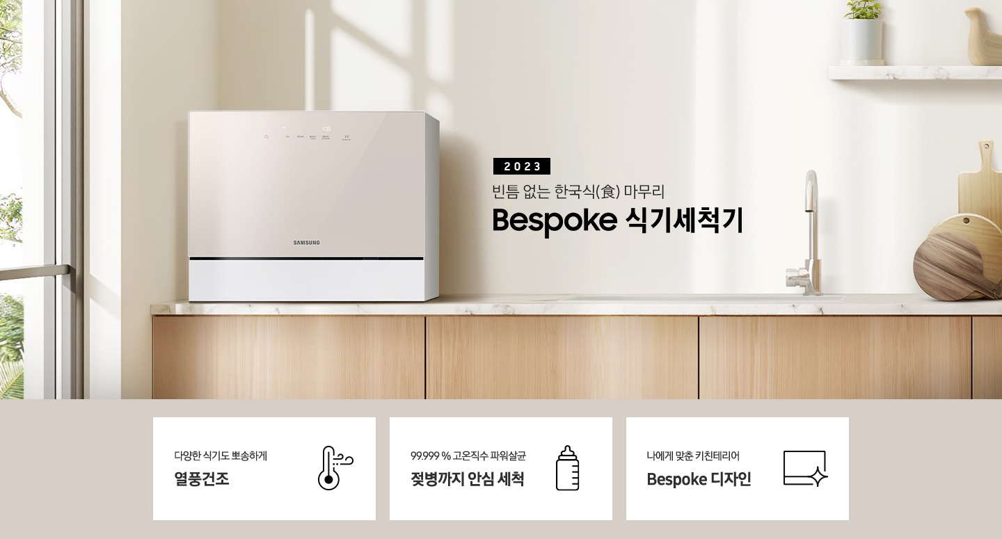 우드 패널 주방 왼쪽엔 창문이 보이고 상판 위 카운터탑 이 올려져 있습니다. 우측에는 2023 빈틈 없는 한국식 마무리 BESPOKE 식기세척기 라는 슬로건이 적여 있고 싱크대 오른쪽엔 수전과, 나무 도마 3개가 있습니다. 그 위 선반에는 작은 식물이 있는 화분과 새 모양의 오브제가 올려져 있습니다.