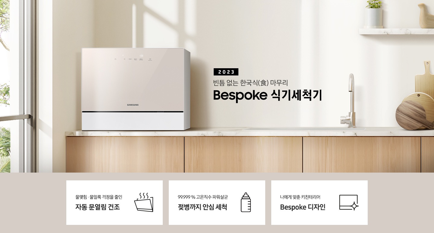 우드 패널 주방 왼쪽엔 창문이 보이고 상판 위 카운터탑 이 올려져 있습니다. 우측에는 2023 빈틈 없는 한국식 마무리 BESPOKE 식기세척기 라는 슬로건이 적여 있고 싱크대 오른쪽엔 수전과, 나무 도마 3개가 있습니다. 그 위 선반에는 작은 식물이 있는 화분과 새 모양의 오브제가 올려져 있습니다.