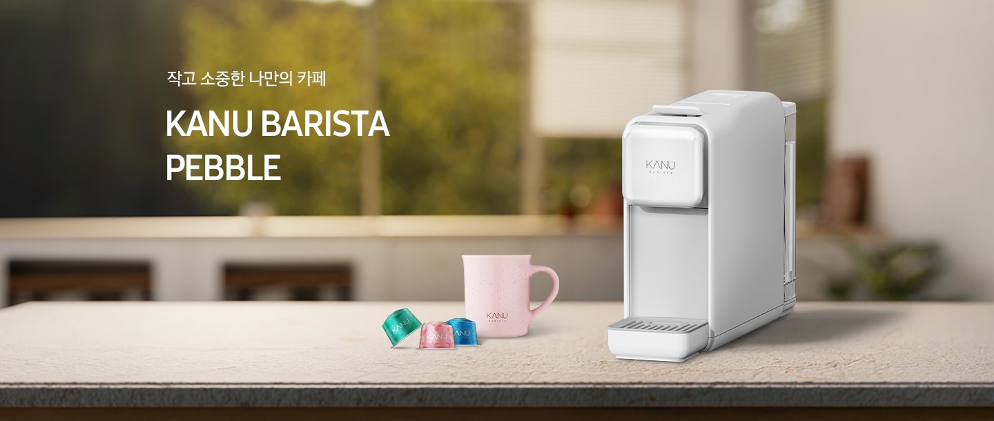 아일랜드 식탁 위 우측에 카누 바리스타 페블 화이트 캡슐 커피머신이 놓여있습니다. 머신 좌측에는 분홍색 카누 머그잔과 카누 캡슐커피머신 전용 캡슐 3개가 놓여있습니다. 좌측에는 문구가 나와있습니다. 작고 소중한 나만의 카페. KANU BARISTA PEBBLE.